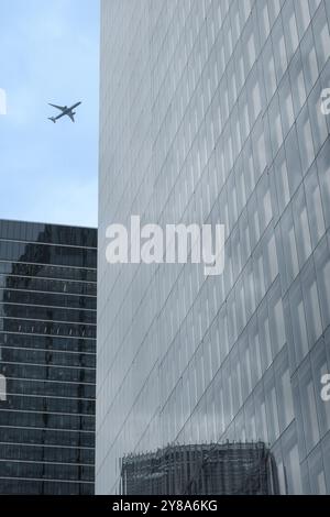 Nahaufnahme moderner Wolkenkratzer mit Glasfassaden auf der Bishopsgate St, City of London, England. Das Flugzeug fliegt im Himmel. Stockfoto