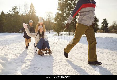Die Familie genießt im Winter die Natur, die auf Schlitten schneebedeckte Pisten hinunter fährt. Glücklich und lachen beim Schlittenfahren Genießen Sie den Nervenkitzel beim gemeinsamen Schlittenfahren Stockfoto