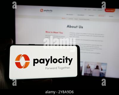 Person, die ein Smartphone mit dem Logo des Softwareunternehmens Paylocity Holding Corporation auf dem Bildschirm vor der Website hält. Schwerpunkt auf dem Display des Telefons. Stockfoto