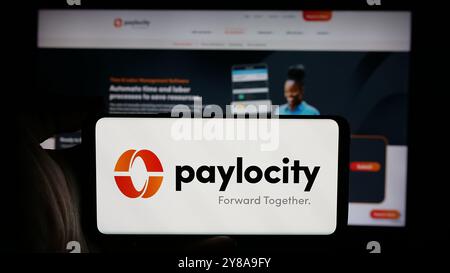 Person, die ein Mobiltelefon hält, mit dem Logo des Softwareunternehmens Paylocity Holding Corporation auf dem Bildschirm vor der Webseite. Schwerpunkt auf dem Display des Telefons. Stockfoto