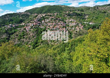 Blick aus der Vogelperspektive auf Lagkadia, ein traditionelles Bergdorf in Arcadia, Griechenland, mit üppigen grünen Hügeln und malerischen Häusern mit roten Dächern. Stockfoto