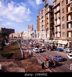 Tägliches Verkehrschaos auf der Meret Basha Straße mit Blick auf das Ägyptische Museum Kuppel und den Ramses Hotelturm in Kairo, nahe vom Midan al Tahrir Platz, Ägypten um 1987. 90010000201 Stockfoto