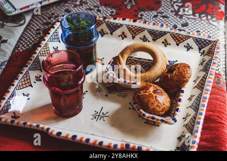 Traditioneller marokkanischer Pfefferminztee und marokkanische Kekse auf einer traditionellen berbere-Platte auf einem roten, traditionellen marokkanischen Teppich Stockfoto