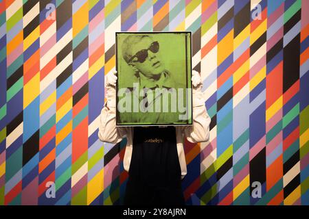 Ein Kunstschaffender hält Andy Warhols Selbstporträt vor Bridget Rileys Gaillard 2, während einer Vorschau für Sotheby's £200 Millionen Kunstwerke verkauft, die Werke von Hockney, Warhol und Picasso enthalten. Bilddatum: Freitag, 4. Oktober 2024. Stockfoto