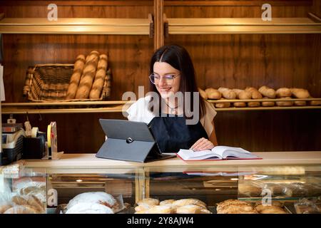 Junge Frau, die tagsüber in einem gemütlichen Geschäft Backwarenbestand verwaltet Stockfoto