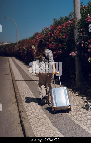 Die Frau zieht ihr Gepäck durch eine kleine Stadt, während sie im Urlaub ist. Stockfoto