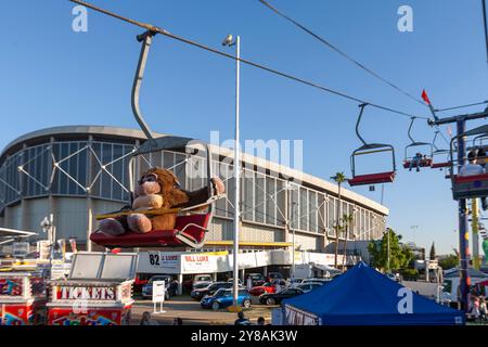 Plüschaffe, die auf dem Messegelände auf einem Skilift fährt Stockfoto