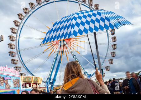 Wiesnbummel im Regen, Oktoberfest, München, Oktober 2024 Deutschland, München, Oktober 2024, Wiesnbummel im Regen, Wiesnbesucherin mit Regenschirm auf der Theresienwiese unterwegs, Riesenrad, Regenwetter, bayerisch, Oktoberfest 2024, Volksfest, Bayern, *** Wiesnbummel im Regen, Oktoberfest, München, Oktober 2024 Deutschland, München, Oktober 2024, Wiesnbummel im Regen, Wiesnbesucher mit Schirm auf der Theresienwiese, Riesenrad, regnerisches Wetter, Bayerisch, Oktoberfest 2024, Volksfest, Bayern, Stockfoto