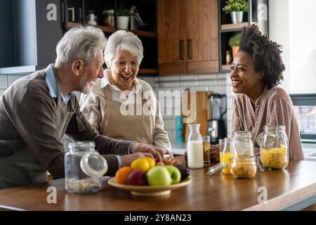 Glückliche multiethnische Familie mit älteren Eltern, die Spaß haben und sich in der Küche unterhalten. Stockfoto