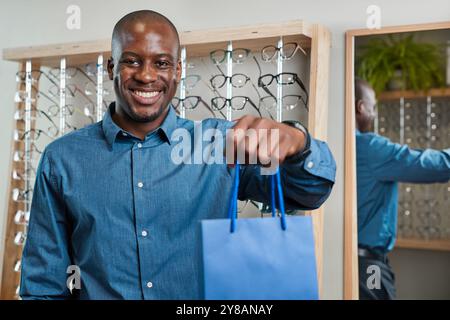 Lächelnder Optometrist hält Einkaufstasche im Brillengeschäft Stockfoto