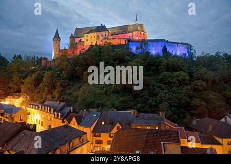 Schloss Vianden, das auf einem Hügel gelegene Schloss thront über der Stadt Vianden, beleuchtet in den Farben der Luxemburger Flagge für den Nationalfeiertag Luxemburgs Stockfoto