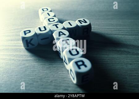 Buchstabenwürfel bilden die Wörter Putin und Diktator in Kreuzform, Buchstabenwürfel formen die Wörter Putin und Diktator (engl.) In Kreuzform Stockfoto