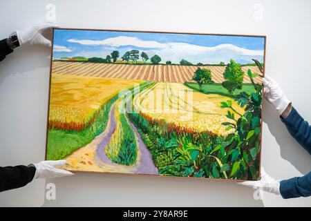 London, Großbritannien. 4. Oktober 2024. Techniker präsentieren „Path through Wheat Field, July“ von David Hockney (Est. £2.000.000 - 3.000.000) bei einer Vorschau auf die Höhepunkte der Frieze Week Modern and Contemporary Art Auctions von Phillips. Die Lose werden am 10. Und 11. Oktober in den Galerien des Berkeley Square von Phillips versteigert. Quelle: Stephen Chung / Alamy Live News Stockfoto