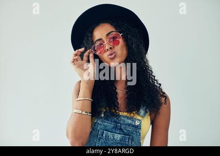 Frau, Porträt und Studio mit Herzsonnenbrille, Selbstbewusstsein und Romantik Emoji in Mode. Weibliche Person, weißer Hintergrund und Symbol für coole Ästhetik Stockfoto