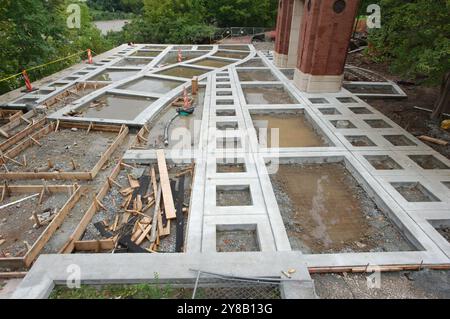 Im Bau unvollendetes Bauprojekt mit Beton und Holz. Orangefarbene Kegel und Schlauch auf dem Boden. Architektur Betongestaltungsplatz Stockfoto