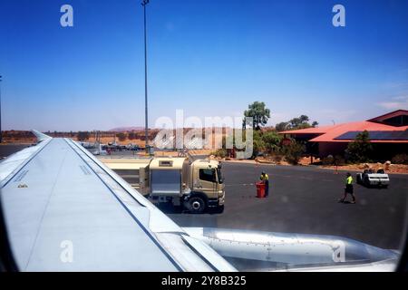 Blick auf den Flugzeugflügel des Tankwagens und den Uluru vom Flughafen Ayers Rock (Connellan Airport) in Yulara, Uluru, Zentralaustralien Stockfoto