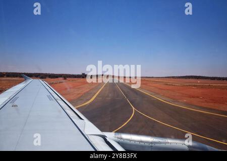 Start vom Flughafen Ayers Rock (Connellan Airport) in Yulara, Uluru, Zentralaustralien, Blick auf die Start- und Landebahn und die rote Wüste Stockfoto