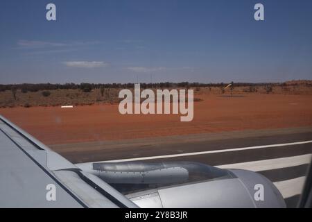 Start vom Ayers Rock Airport, Connellan Airport in Yulara, Uluru, Zentralaustralien, Blick auf die Start- und Landebahn und die rote Wüste von einem Sitz über dem Flügel Stockfoto