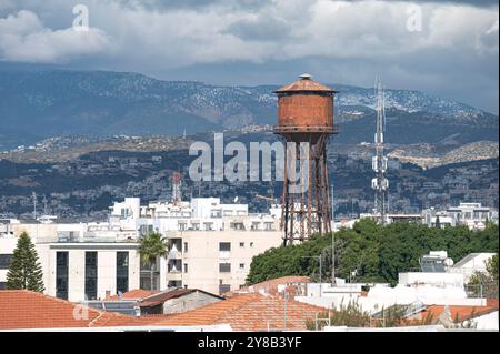 Der alte, rostige Wasserturm dominiert die Skyline von Limassol, Zypern, mit den Troodos-Bergen im Hintergrund Stockfoto