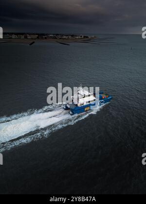 Luftaufnahme eines blau-weißen Offshore-Katamarans bei hoher Geschwindigkeit an der Küste der Insel Norderney in der Nordsee Deutschlands. Stockfoto