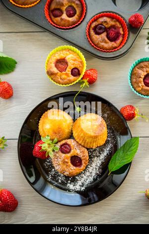 Süße Quark-Muffins mit Erdbeerfüllung, auf einem Teller auf einem Holztisch. Stockfoto