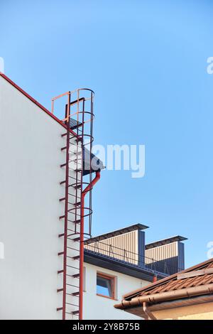 Sichern Sie die Treppen zum Dach des Gebäudes. Metall. Rot. Vertikaler Shot für Industriegebäude Stockfoto