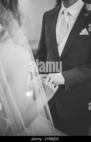 Braut legt den Ring auf die Hand des Bräutigams Stockfoto