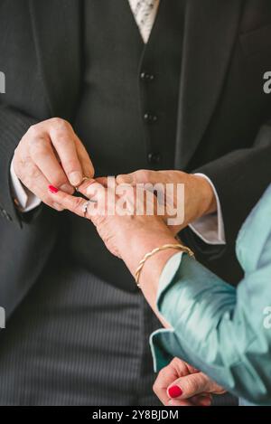 Der ältere Bräutigam legt den Ring an die Hand der Bräute Stockfoto