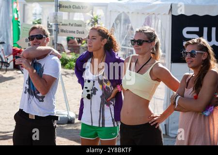 DREI VOLLEYBALLSPIELER SCHAUEN ZU, BEACHVOLLEYBALL, MARIEHAMN, 2011: Drei Volleyballspieler beobachten während der Qualifikationsstufen. An einem ungewöhnlich heißen Sommertag in der Ostsee im August 2011 bei den PAF Open in Mariehamn, Åland, Finnland, beobachten die Menschen die Beachvolleyball-Action auf den Außenplätzen in Sommerkleidung oder Strandbekleidung. Foto: Rob Watkins. INFO: Das PAF Open Beach Volleyballturnier fand zwischen 2009-2013 in Mariehamn, Åland, Finnland statt. Es zog die besten internationalen Teams und Spieler als Rangliste der offiziellen FIVB World Tour, Showcasi, an Stockfoto