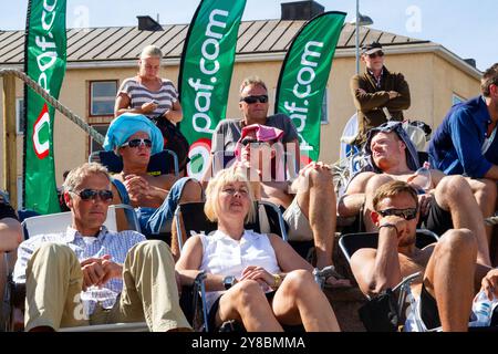 FANS IN LIEGESTÜHLEN SCHÜTZEN VOR DER SONNE, BEACHVOLLEYBALL, MARIEHAMN, 2011: Fans improvisieren, ihren Kopf vor der brennenden Sonne zu bedecken. An einem ungewöhnlich heißen Ostsee-Sommertag im August 2011 bei den PAF Open in Mariehamn, Åland, Finnland, beobachten die Menschen die Beachvolleyball-Action in entspannenden Liegestühlen auf den Außenplätzen in Sommerkleidung oder Strandbekleidung. Foto: Rob Watkins. INFO: Das PAF Open Beach Volleyballturnier fand zwischen 2009-2013 in Mariehamn, Åland, Finnland statt. Es zog die besten internationalen Teams und Spieler als Rangliste der offiziellen FIVB World Tour an. Stockfoto