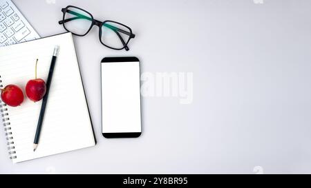 Draufsicht auf einen modernen Arbeitsbereich mit Smartphone mit leerem Bildschirm und Tastatur. Bürosituation mit Tastatur und Zubehör auf weiß isoliert. Kopie sp Stockfoto