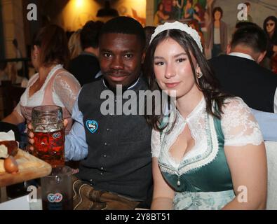 München, Deutschland, 01. Oktober 2024: Fussball, Herren, 3.Liga, Saison 2024/2025, TSV 1860 München, Wiesn, Wiesnbesuch, Oktoberfest, Hacker Festzelt Leroy Kwadwo (TSV 1860 München) (li.) mit einer Mass Bier in der Hand, in Tracht, hier mit seiner Begleitung Stockfoto