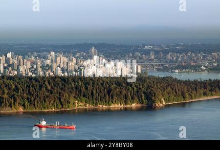 Während ein Frachter durch das Wasser gleitet, erstrahlt die zerklüftete Küste von Vancouver Island in British Columbia im Glanz der späten Nachmittagssonne. Stockfoto