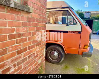 Ein orangener devon Edition Volkswagen Wohnmobil parkt neben einer roten Backsteinmauer in somerset england, Großbritannien Stockfoto