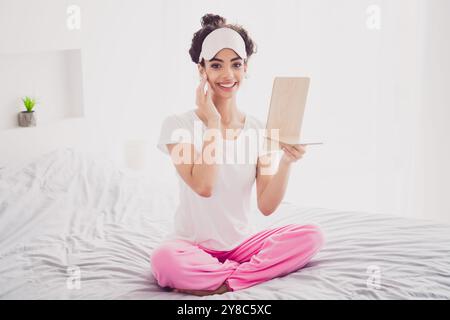 Foto von schönen amerikanischen süßen jungen Mädchen im Pyjama aufwachen Guten Morgen gemütliche Schlafzimmer vergrößern Glas Routine Schönheit Hautpflege Stockfoto