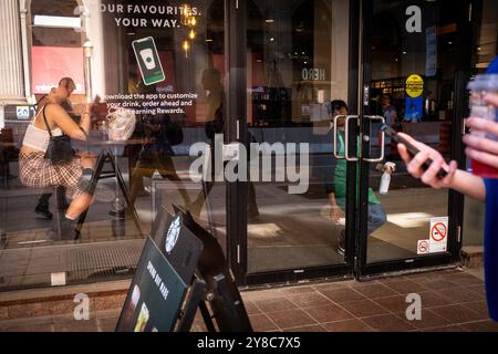 Person, die ihr Smartphone vor einem Starbucks-Café mit einem Mitarbeiter in Toronto, der Wirtschaftshauptstadt Kanadas in der Provinz, besucht Stockfoto