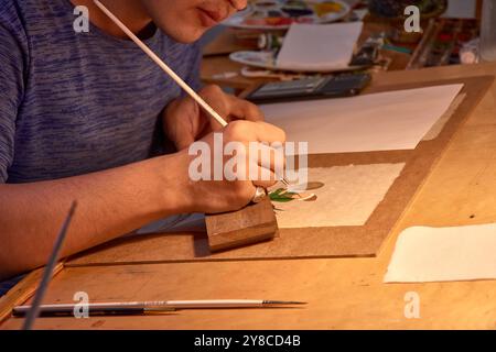 Dieses fesselnde Bild zeigt die geschickten Hände einer handwerklichen Holzmalerei auf einem der pulsierenden Basare von Buchara, Usbekistan. Bekannt Stockfoto