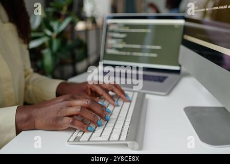Mittlere Nahaufnahme von gepflegten Händen, die auf der weißen Tastatur tippen Stockfoto