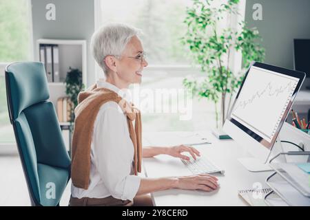Foto von intelligenter älterer Chef weiblicher Arbeitscomputer Kleidung formalwear komfortable moderne Büro Loft Raum innen Arbeitsplatz Stockfoto