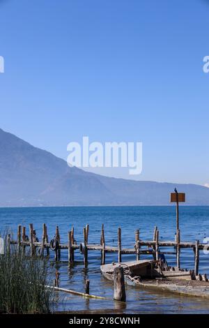 Ein halb untergetauchtes Schiff auf dem Atitlan-See. Rustikaler, alter Steg im Dorf Palopo. Ruhiger See im guatemaltekischen Hochland, Zentralamerika. Stockfoto