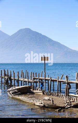 Ein halb untergetauchtes Schiff auf dem Atitlan-See. Rustikaler, alter Steg im Dorf Palopo. Ruhiger See im guatemaltekischen Hochland, Zentralamerika. Stockfoto