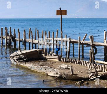 Ein halb untergetauchtes Schiff auf dem Atitlan-See. Rustikaler, alter Steg im Dorf Palopo. Ruhiger See im guatemaltekischen Hochland, Zentralamerika. Stockfoto