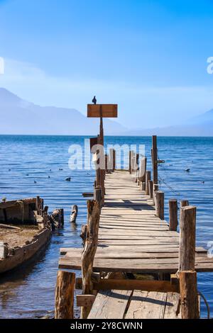 Ein halb untergetauchtes Schiff auf dem Atitlan-See. Rustikaler, alter Steg im Dorf Palopo. Ruhiger See im guatemaltekischen Hochland, Zentralamerika. Stockfoto