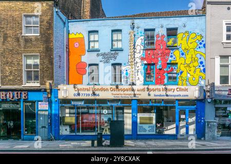 Zentrale Londoner Osteopathie- und Sportverletzungsklinik in der Old Street, Hackney. Die Vorderseite des Gebäudes ist mit Street Art Wandgemälden bedeckt. Stockfoto