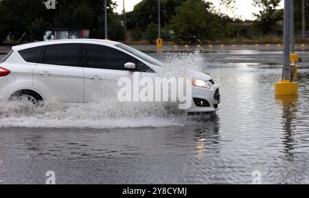 Nach starken Regenfällen bildeten sich Staus auf den Straßen, Autos werden mit Wasser übergossen und stehen. Autos schweben in Pfützen auf den Straßen, Spritzer. Straßeneinsturz hinten Stockfoto