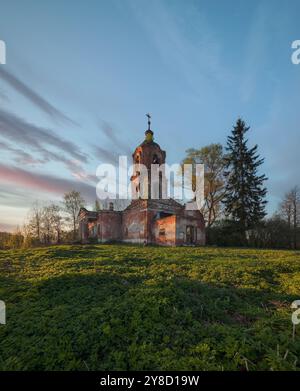 Eine alte, verlassene Kirche aus Backstein mit einem Glockenturm bei Sonnenuntergang Stockfoto