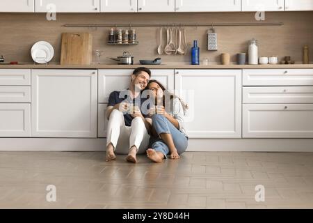 Glückliche zwei Hausbesitzer, die dicht nebeneinander auf dem Boden sitzen Stockfoto