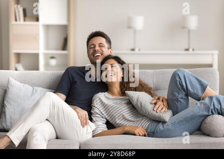 Fröhliches verheiratetes Paar, das sich auf einem bequemen Sofa ausruht Stockfoto