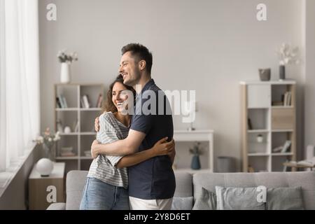 Glückliches junges Familienpaar, das in einem komfortablen Innenraum steht Stockfoto