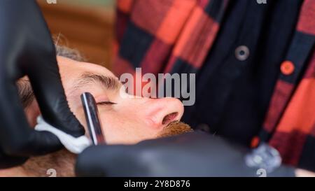 Bärtiger Mann. Professionelle Bartpflege. Bärtiger Mann im Friseur. Friseursalon, der Gäste im Friseurladen bedient. Rasierer, Friseurladen. Vintage barbe Stockfoto